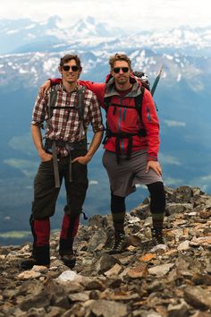 two men standing on top of a rocky mountain