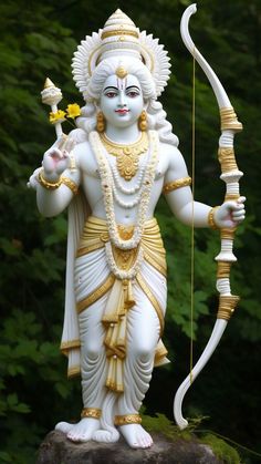 a statue of a hindu god with a bow and arrow in his hand, standing on a rock