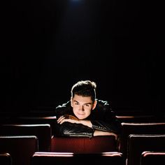 a young man is sitting in an empty theater