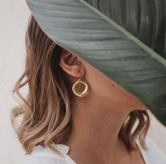 a woman wearing a white shirt and large gold hoop earring on her left ear