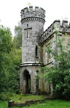 an old stone castle with a cross on the front and side entrance, surrounded by trees