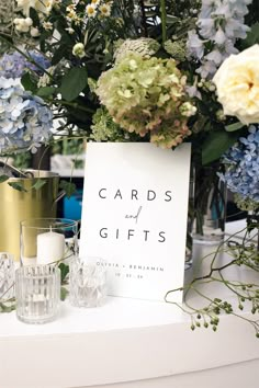 flowers and candles are sitting on a table with cards and gifts in front of them