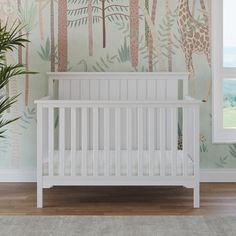 a white crib in front of a wall with giraffes and trees on it