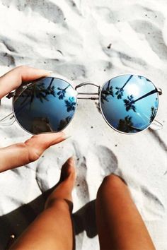 a person is holding their sunglasses on the beach with palm trees reflected in them and text reading ray ban $ 50 for gift, press picture link to get it