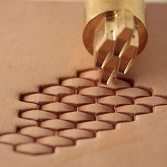 a close up of a carving tool on a piece of wood with hexagonal shapes