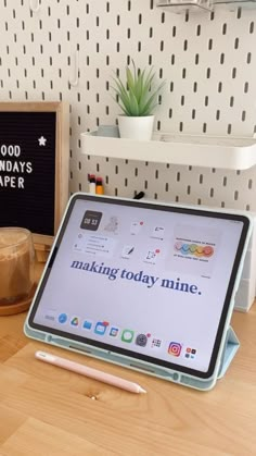 a tablet sitting on top of a wooden table next to a cup of coffee and a pen