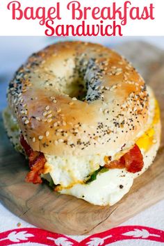 bagel breakfast sandwich with bacon and egg on a wooden cutting board next to a red ribbon