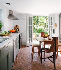 a kitchen with an open door leading to the dining room and patio area, along with brick flooring