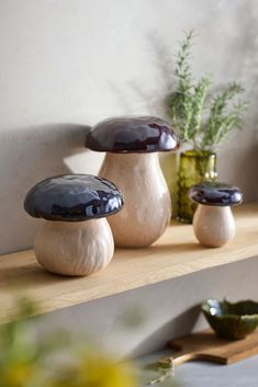 three ceramic mushrooms sitting on top of a wooden shelf