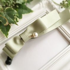 a close up of a tie on a white frame with green plants in the background