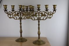 an ornate brass candelabra with five candles on it's sides, sitting on a wooden table