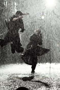 two people jumping in the air on a rainy day