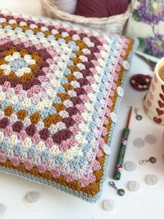 a crocheted blanket sitting on top of a table next to a coffee cup