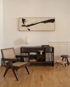 a living room with two chairs and a book shelf on the wall next to a painting