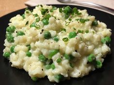 a black plate topped with mashed potatoes and peas