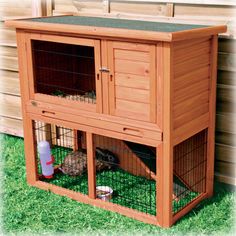 a large wooden chicken coop with two small chickens in it's hutch on the grass