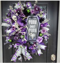 a wreath with purple and white decorations on it that says, zombie sweet bomb in front of a black door