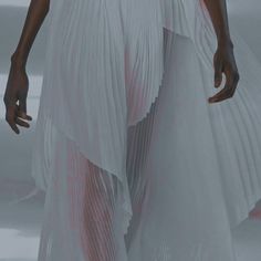 a woman in a white dress walks down the runway with her hand on her hip