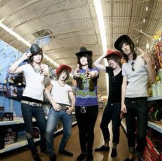 four young people are standing in a store with hats on and one is pointing at the camera