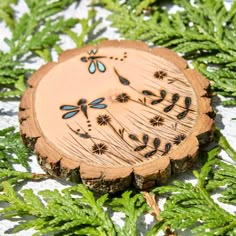 a piece of wood with dragonflies on it and some green leaves around the edges