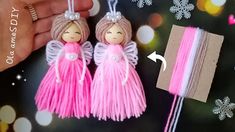 two pink tasselled angel ornaments being held by someone's hand and string