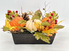 an arrangement of autumn leaves, pumpkins and berries in a wooden box on a white background