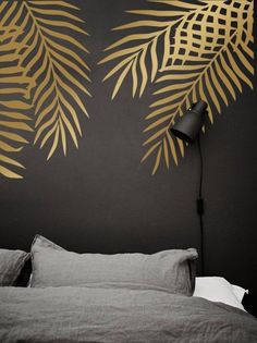 a black and gold bedroom with palm leaves on the wall