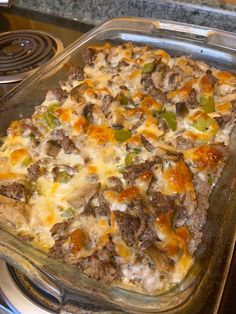 a casserole dish with meat, cheese and vegetables in it on top of a stove