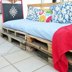 a couch made out of wooden pallets sitting on top of a tiled floor next to a window