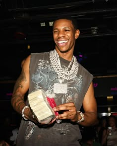 a young man holding a piece of cake in his right hand and smiling at the camera