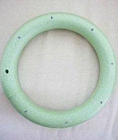 a close up of a green ring on a white surface with holes in the middle