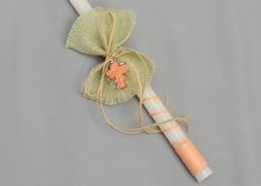 a white candle with a cross on it sitting next to a green organine bag