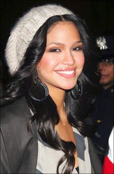 a beautiful young lady wearing large earrings and a beanie