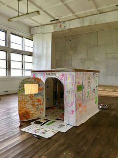 a room with wooden floors and walls covered in drawings on the floor, including a dog house