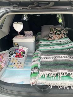 the trunk of a car is packed with blankets, pillows and other decorative items in it