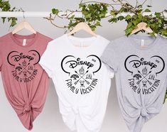 three t - shirts hanging on a clothes rack with disney and mickey mouse heads printed on them