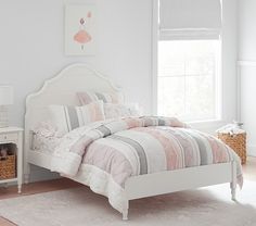 a white bed with pink and grey comforter in a bedroom