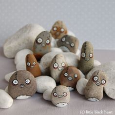 several rocks with faces and eyes are arranged in a pile on a tablecloth covered surface