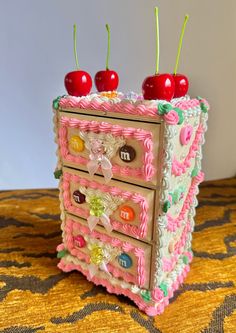 a cake shaped like a chest with cherries on it's top and drawers