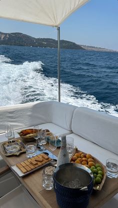 a table with food and drinks on the back of a boat in the open water