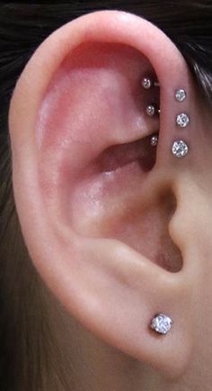 a woman's ear with three different piercings