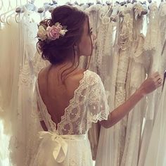 a woman looking at wedding gowns in a bridal shop with her back to the camera