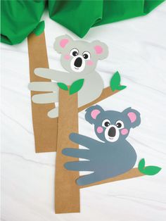 two paper koalas sitting on top of a tree