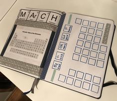 an open book with the word march written in blue and white on it, sitting on top of a table