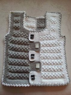 two knitted vests with buttons on the front and back, sitting on a bed