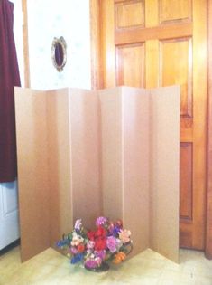 a room divider in front of a door with flowers on the floor next to it