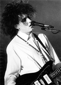 black and white photograph of a man playing an electric guitar in front of a microphone