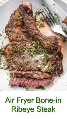 a steak on a white plate with a fork and knife next to it that says air fryer bone - in ribeye steak