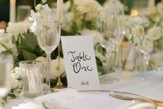 the table is set with white flowers and place cards for guests to write their names