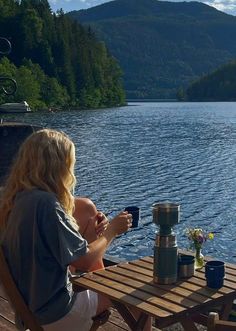 a woman sitting at a wooden table on top of a lake